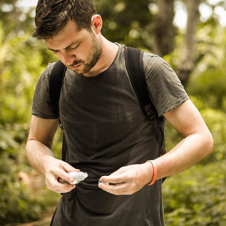 Man opening a bottle of Genus Expedition Natural Mosquito Repellent