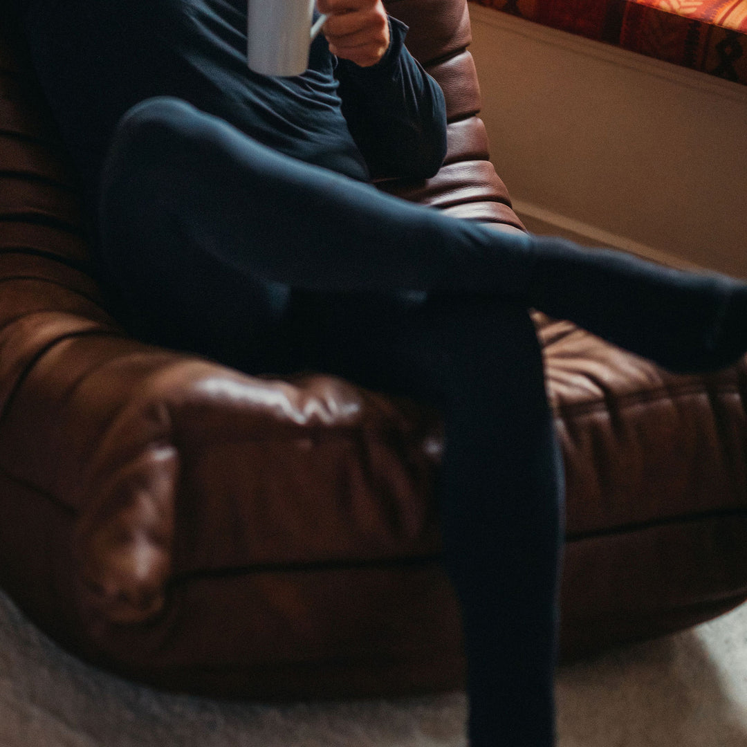 Man on a sofa in the Genus Men's Merino Blend Thermal Leggings
