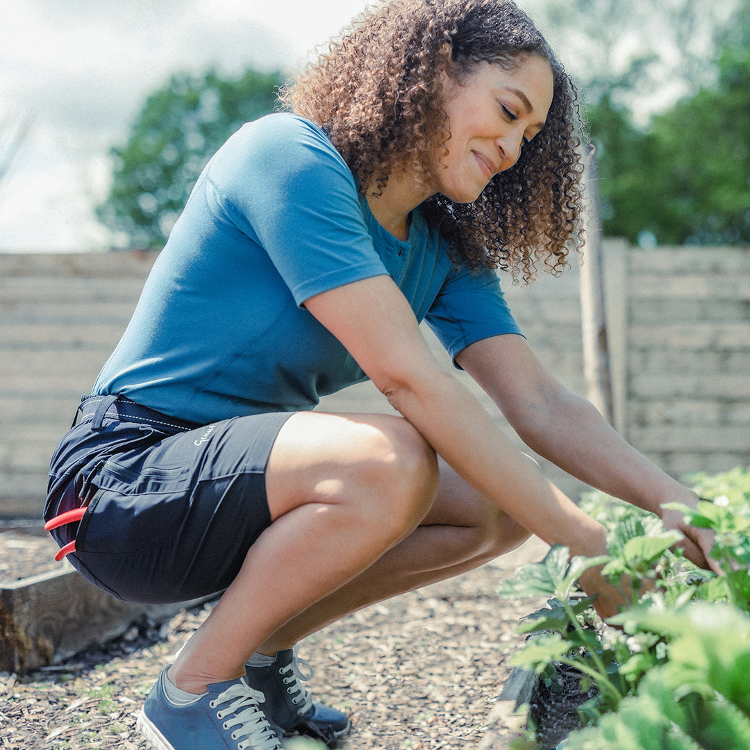 Woman in her garden wearing the Genus Women's Summer Gardening Shorts Dark Navy